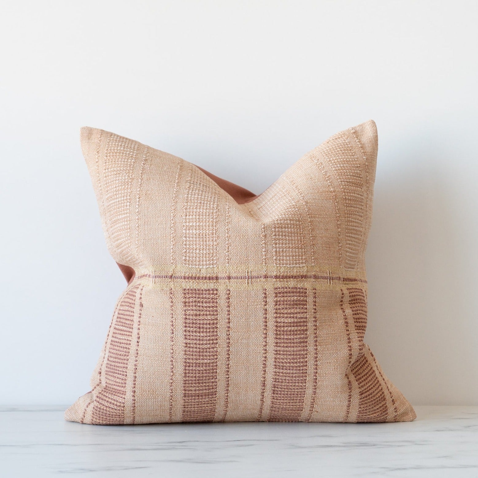 Textured woven pillow with tones of beige and rosy clay